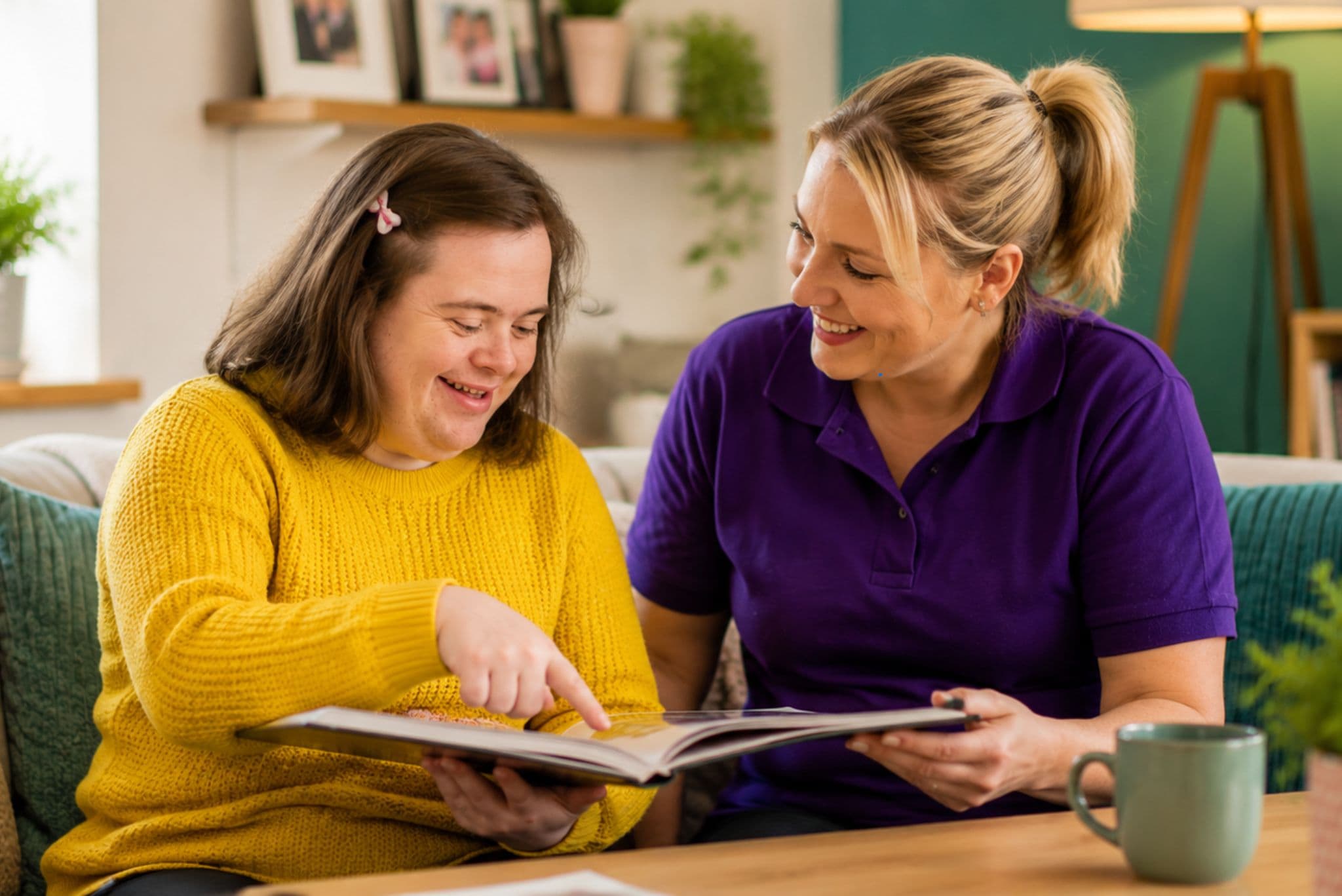 A carer and a young woman enjoying a book together at home